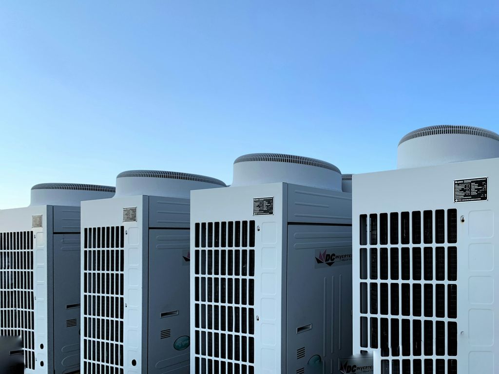 Row of large outdoor condensing units on a rooftop under a blue sky