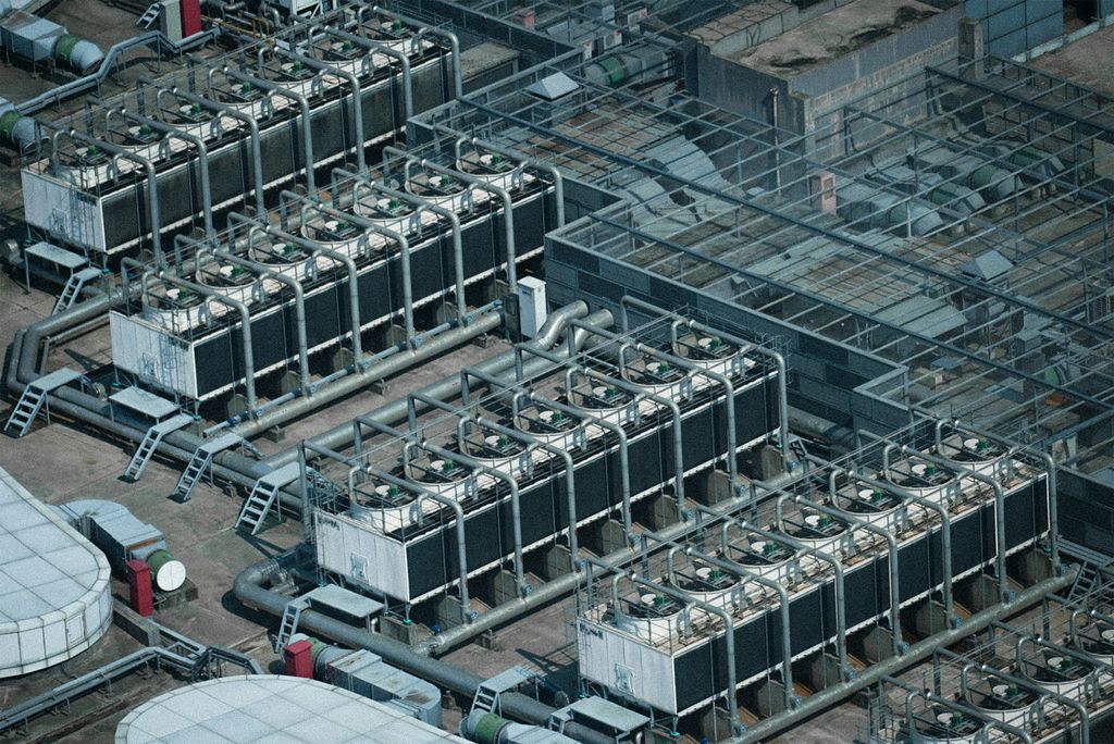 Aerial view of rows of rooftop cooling equipment and piping at an industrial site